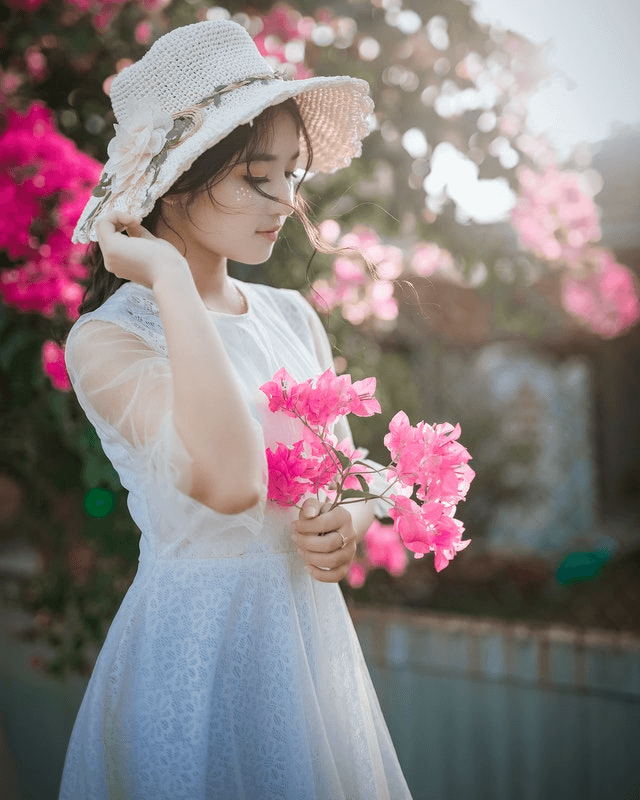 This example creates an inverted PNG picture of a girl with a hat holding pink flowers. The inversion area covers the entire picture and turns the pixels in the girl's white hat and white dress into black pixels and pixels of the pink flowers into pixels of green shades. (Source: Pexels.)